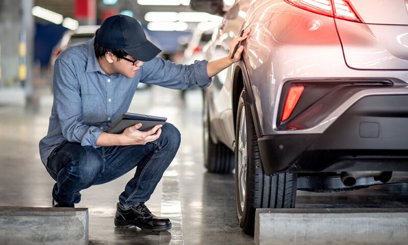 Ein Mann untersucht den Reifen an einem Fahrzeug